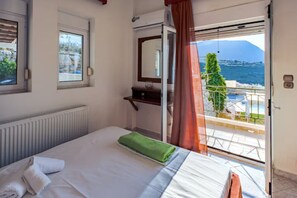 Ein Hotelzimmer mit Bett, Fenster, Spiegel, Heizkörper und Meerblick.