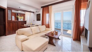 A living room with a beige sofa, a wooden coffee table, and a view of the balcony. - Aptera Dream Apartment (Souda)