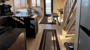 Interior acollidor d'una cabana amb cuina, zona de menjador i un ventilador de sostre.