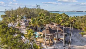 Une propriété située en bord de mer, comprenant plusieurs bâtiments, des palmiers et une piscine.