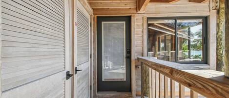 A wooden exterior with a sliding door, a small porch with a wooden railing, and a view of the outdoors.