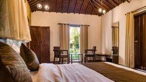 Un dormitorio con una cama grande, dos sillas, una mesita y una ventana con cortinas.