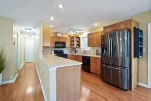 A modern kitchen with wooden cabinets, stainless steel appliances, and a central island. - Evergreen Grove | Hocking Hills, Hot Tub, Firepit (Sugar Grove)