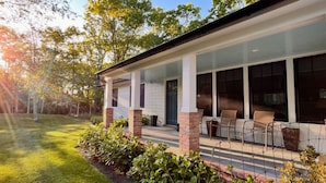 Et moderne hus med en overdækket veranda, store vinduer og en velplejet græsplæne.