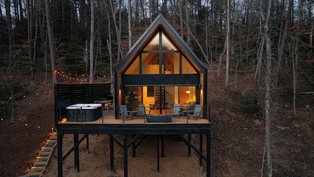 Eine Hütte mit Terrasse, Whirlpool und Sitzgelegenheit.