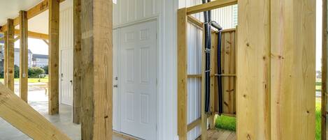 A wooden deck with a white door and a black hose running along the wall.