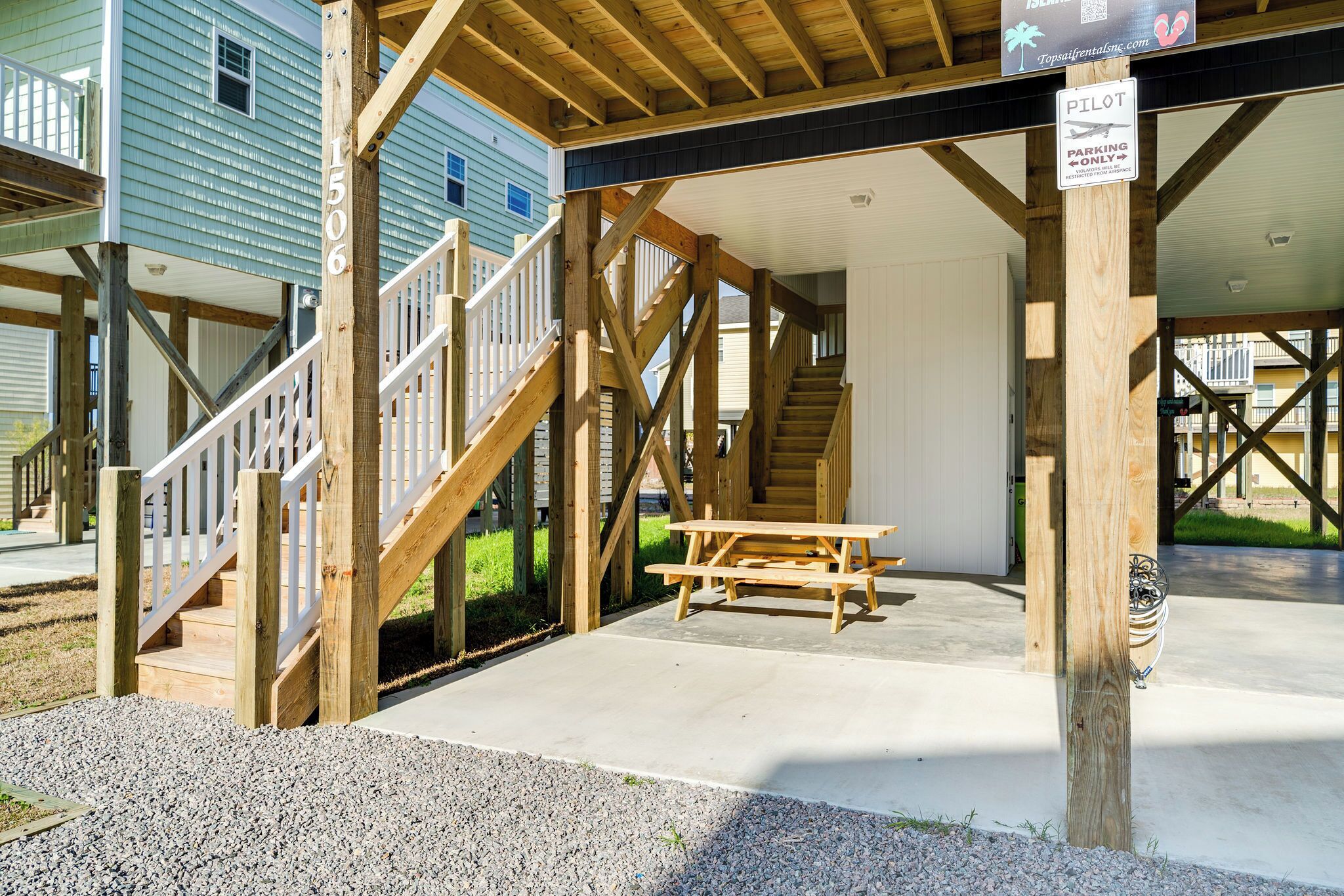 Une terrasse en bois avec une table de pique-nique, un escalier et un panneau indiquant une place de stationnement réservée aux « PILOTES ».