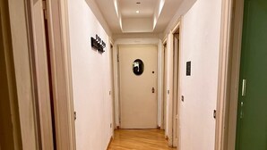 A hallway with wooden flooring, white walls, and a green door at the end. - Elegant & Large flat for Family and Groups (Milano)