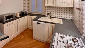 A compact kitchen with white cabinets, a built-in microwave, a gas stove, and a sink. - Elegant & Large flat for Family and Groups (Milano)