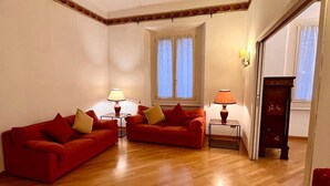 A living room with two red sofas, a small table with a lamp, and a window with curtains. - Elegant & Large flat for Family and Groups (Milano)