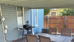 Une terrasse extérieure avec une table et des chaises, un barbecue et un espace abrité.