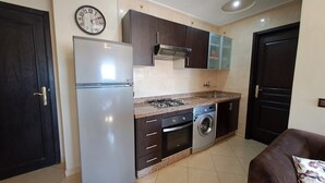 Cocina compacta equipada con refrigerador, estufa, microondas y lavadora.