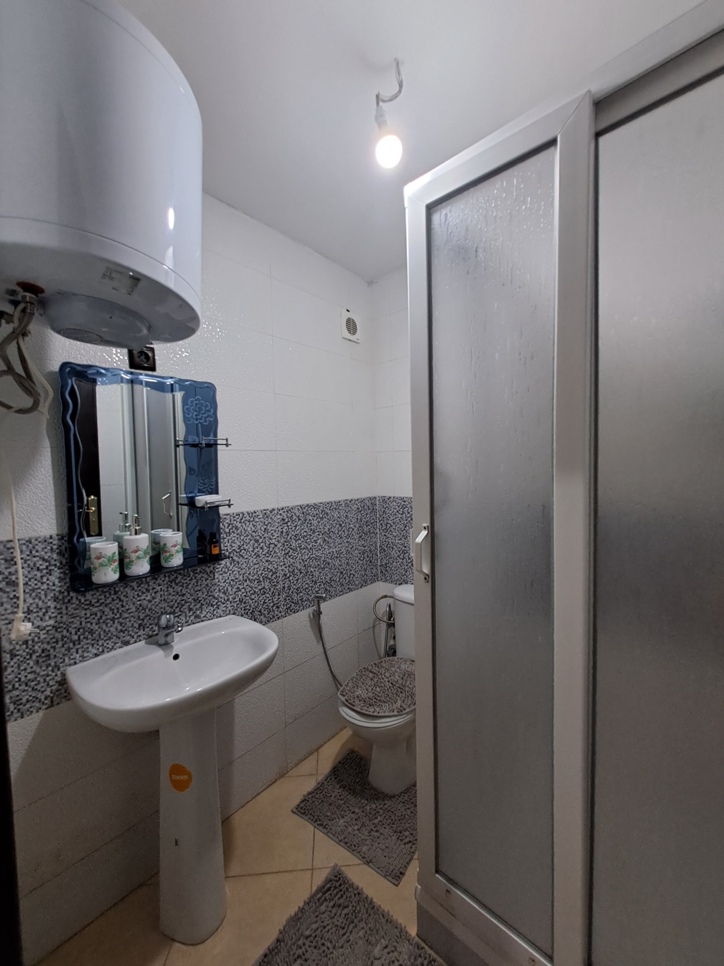 A bathroom with a white sink, a toilet, and a shower. There is a mirror above the sink and a towel rack.