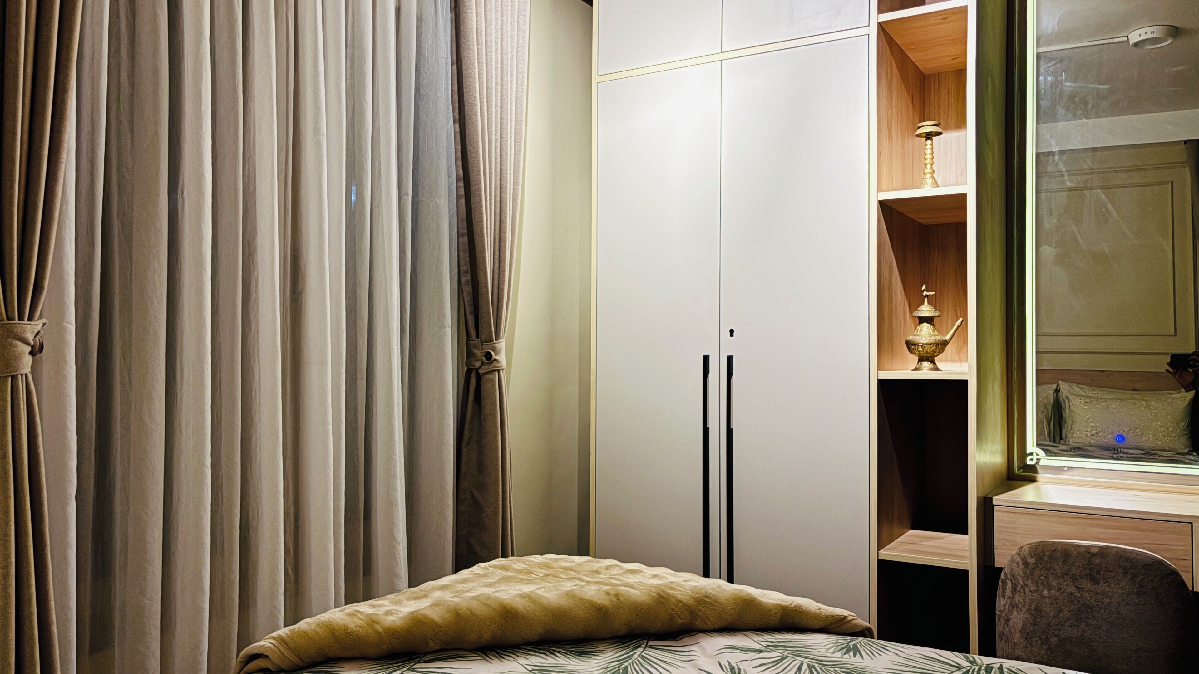 Een slaapkamer met een bed, een kledingkast, een spiegel en een nachtkastje.