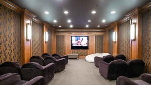 A home theater room with a flat-screen TV, multiple plush seating, carpeted floor, and patterned wallpaper. - Powderhorn Suite-Ski/Out, Hot Tub w/ Mountain View (Brighton)