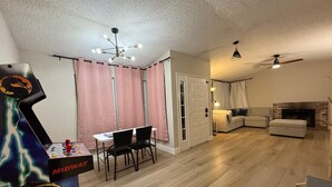 A living room with a foosball table, a sofa, a fireplace, and a ceiling fan. - Spacious 4-bedroom house with AC in charming Roseville (Roseville)