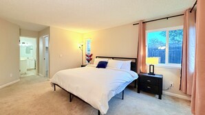 A bedroom with a bed, nightstand, lamp, and window with curtains. - Spacious 4-bedroom house with AC in charming Roseville (Roseville)
