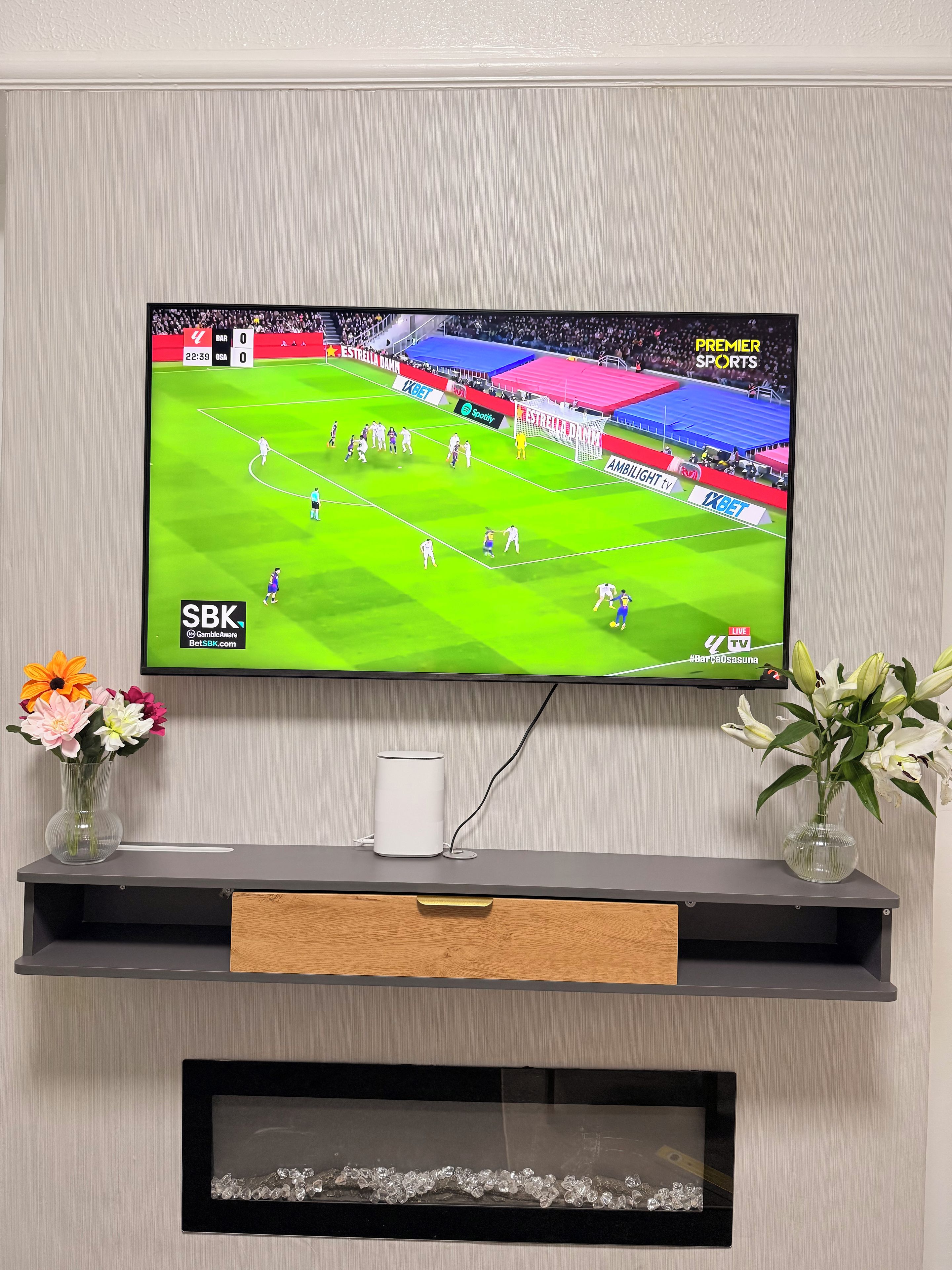 A flat-screen TV mounted on a wall, displaying a sports event.
