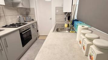 A modern kitchen with a gas stove, oven, and a sink. There are cabinets and a blue range hood.