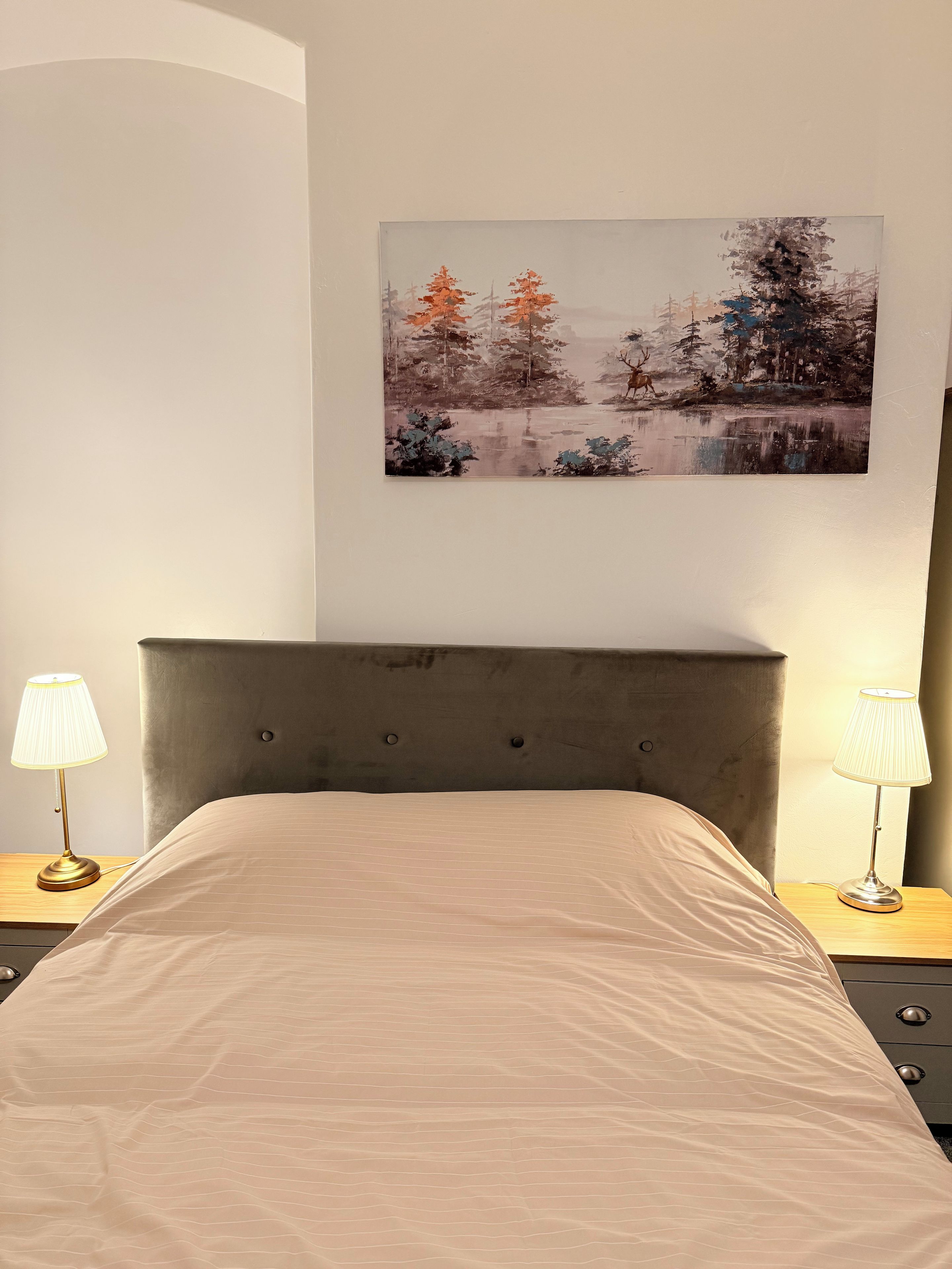 Une chambre à coucher avec un lit, deux lampes de chevet, un tableau accroché au mur et une table de chevet.