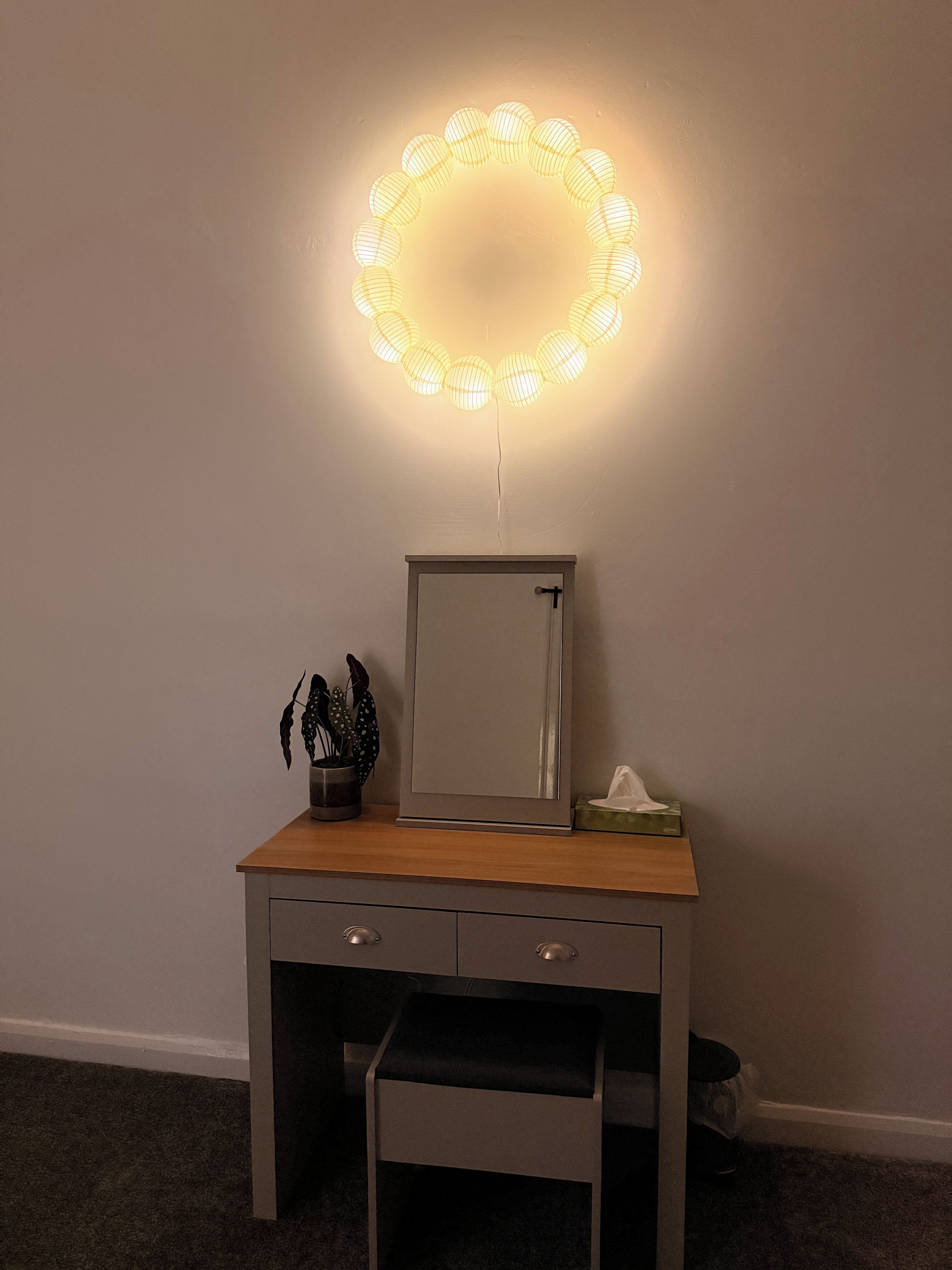 A vanity with a mirror, a small stool, and a light fixture above.