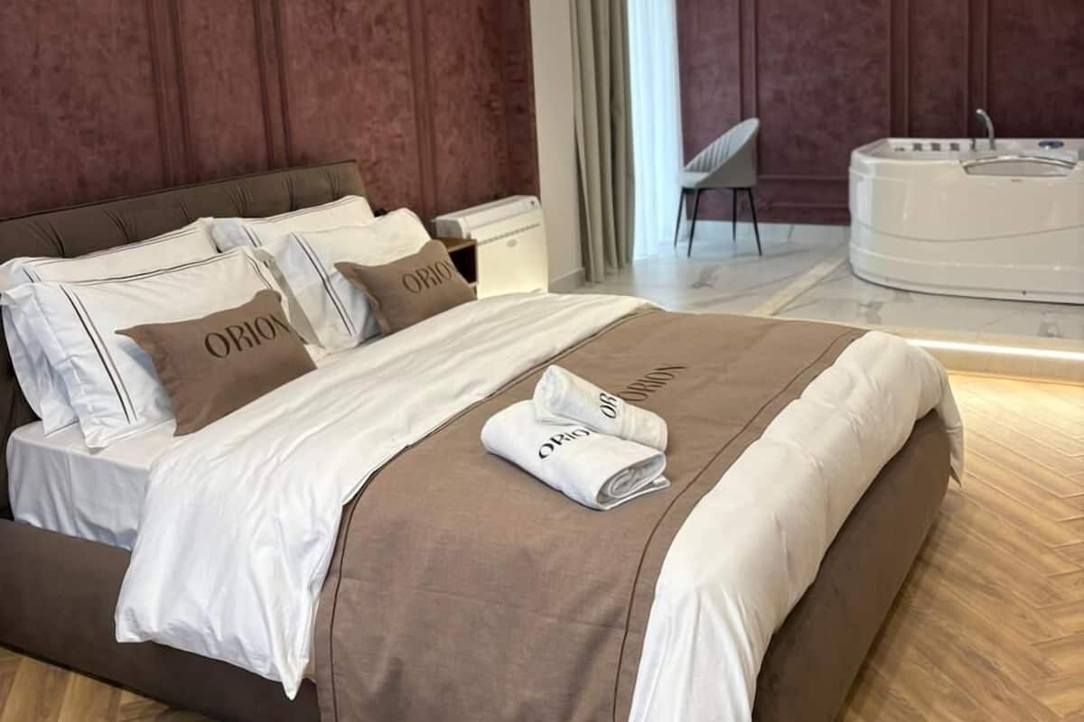 Un dormitorio moderno con una cama grande, una mesa redonda blanca y una silla.