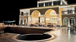 Un edificio con piscina, mobiliario exterior y un balcón.