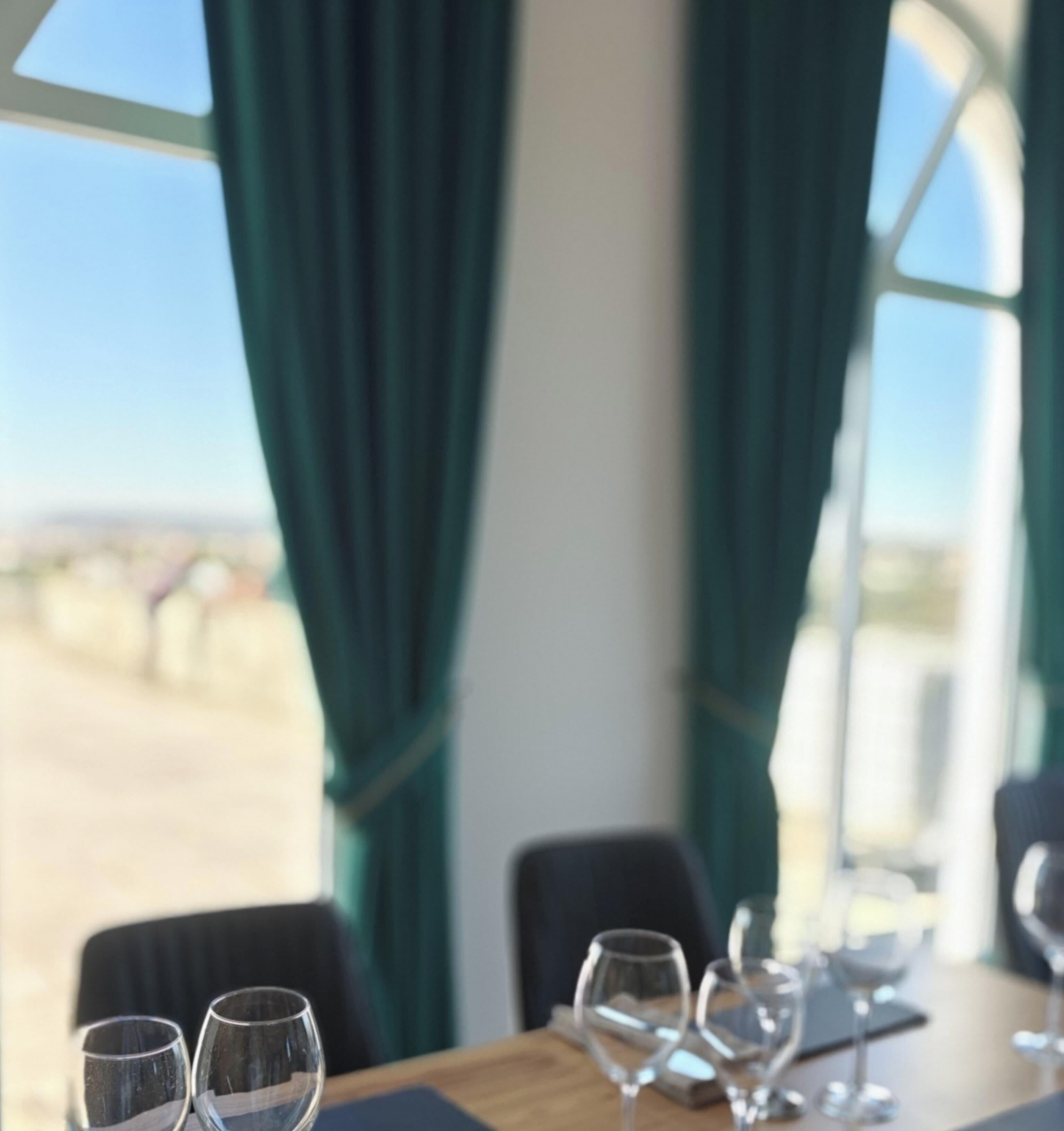Een eettafel met lege wijnkaraffen en uitzicht op een woestijnlandschap door grote ramen.