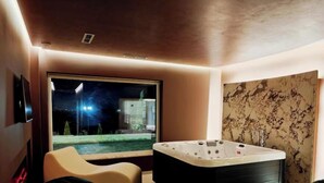 Un baño moderno con un ventanal grande, una bañera y vistas a un paisaje nocturno.