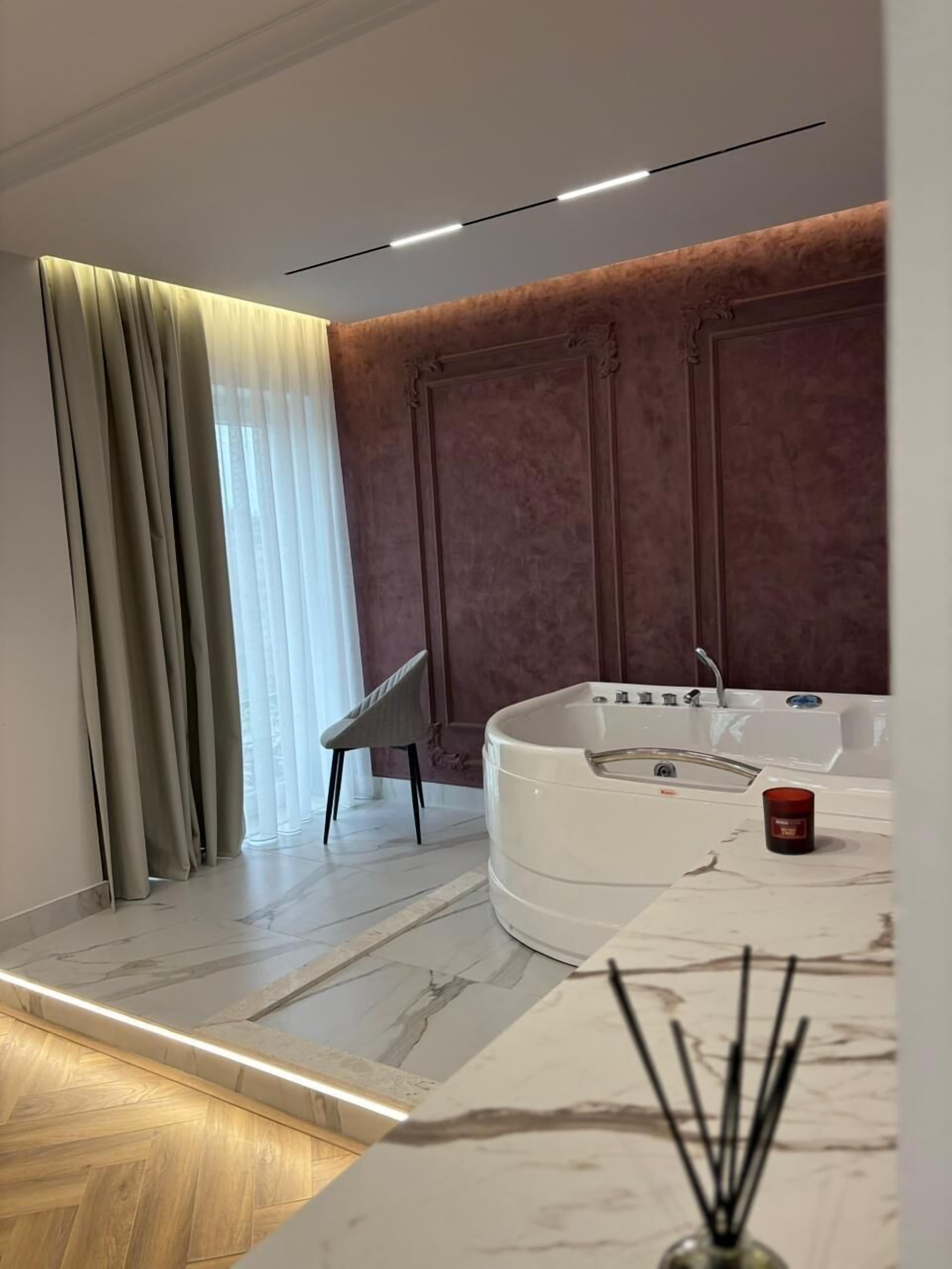 Ein modernes Badezimmer mit einer freistehenden Badewanne, einem großen Spiegel und Holzboden.