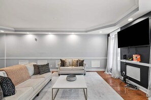 Ett modernt vardagsrum med en soffa, ett soffbord och en tv som står på ett TV-bord.