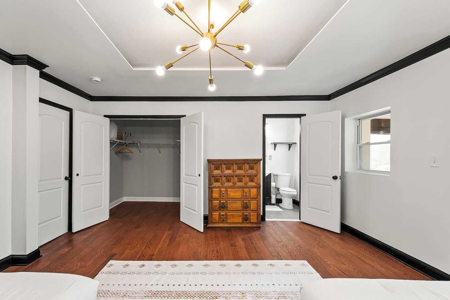 A spacious room with a wooden floor, a central wooden cabinet, and a ceiling light fixture.