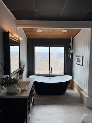 Ein modernes Badezimmer mit freistehender Badewanne, einem großen Fenster und einer Holzbeschreibung.