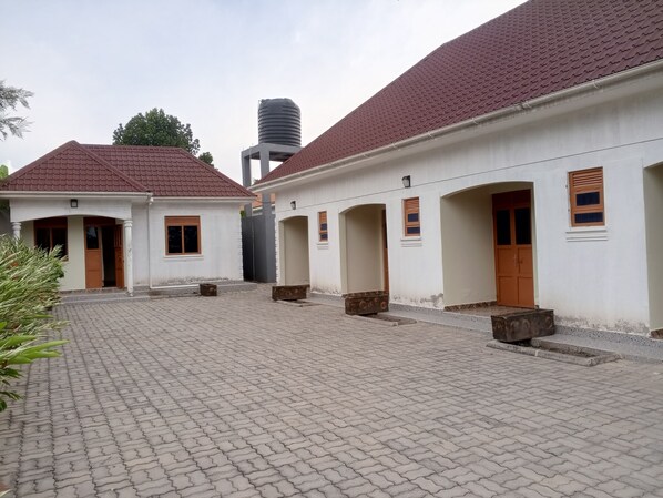 A courtyard with two-story buildings, a water tank, and a paved walkway.