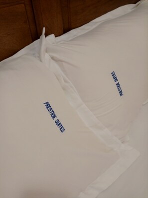 A bed with white bedding and text indicating "PRESTIGE SUITES".