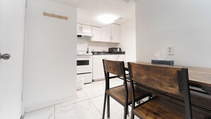 A modern kitchen with white cabinets, a wooden dining table, and a black chair. - Cozy Private 2 bedroom apartment, free Wifi, free parking in heart of Toronto (Toronto)