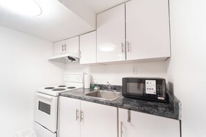 A kitchen with white cabinets, a stainless steel sink, a stove, and a microwave. - Cozy Private 2 bedroom apartment, free Wifi, free parking in heart of Toronto (Toronto)