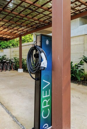 Eine Ladestation mit einem QR-Code, einem Kabel und einem Fahrrad in der Nähe.