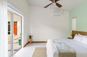 A bedroom with a bed, a ceiling fan, a sliding glass door, and a small plant. - 3-Bedroom Jungle Villa with Pool & FirePit in lovely Puerto Viejo (Puerto Viejo de talamanca)