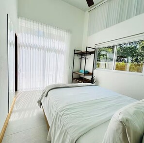 Quarto com cama, janela com vista para o verde e estante de metal.