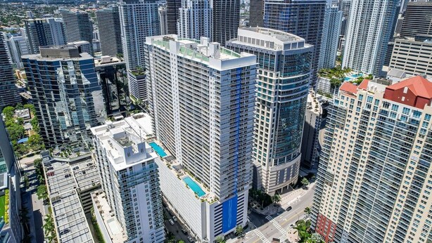 A high-rise urban area with modern skyscrapers, a prominent curved building, and a rooftop pool. - Stylish 1BR Brickell Retreat Walk to Everything (Miami)