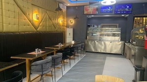 A restaurant interior with booth seating, a counter with a display case, and a digital menu board. - P1 Place Hotel (Lagos)
