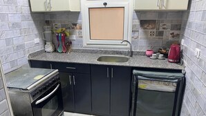 Uma cozinha compacta com forno embutido, pia e uma pequena geladeira.