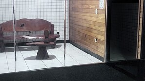 A lobby with a wooden bench, a tiled wall, and a black floor. - Braz Hotel (Tomé-Açu)
