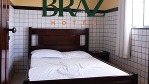 A hotel room with a bed, a nightstand, and a window with curtains. - Braz Hotel (Tomé-Açu)