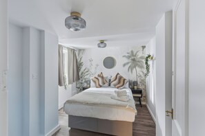 Een slaapkamer met een bed, nachtkastjes, een plafondlamp en uitzicht op buiten.