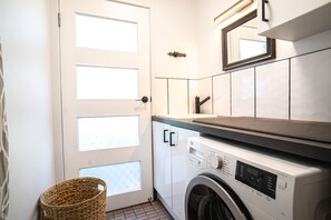 A laundry room with a washing machine, a drying rack, and a basket. - Paws and Palms Hideaway in Nelson Bay (Nelson Bay)