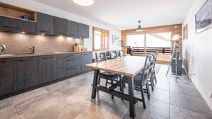 Eine moderne Küche mit dunklen Schränken, einem Holztisch und einem großen Fenster, das natürliches Licht hereinlässt.