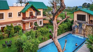 A resort with multiple two-story buildings, a swimming pool, and lush greenery. - Corbett Mystic Inn An ExclusiveBoutique  (Ramnagar)