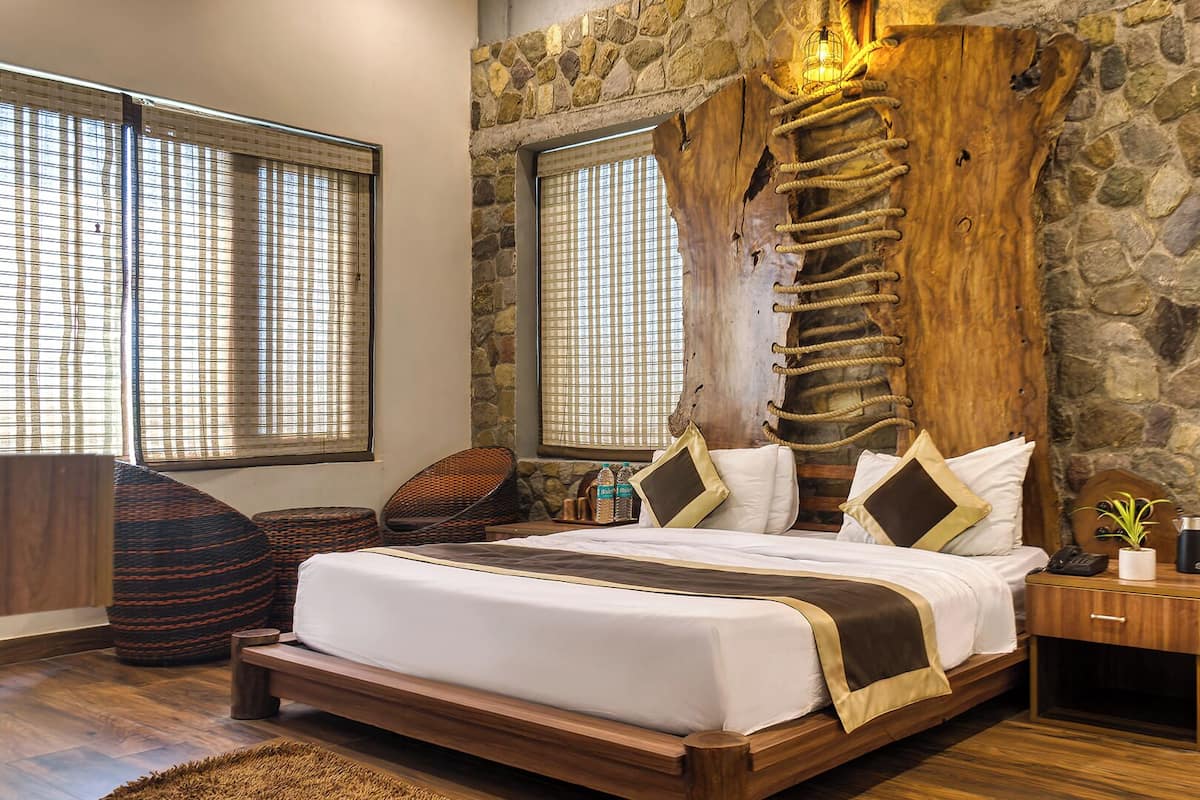 A bedroom with a stone wall, a wooden headboard, a bed with white bedding, a nightstand, and a window with blinds.